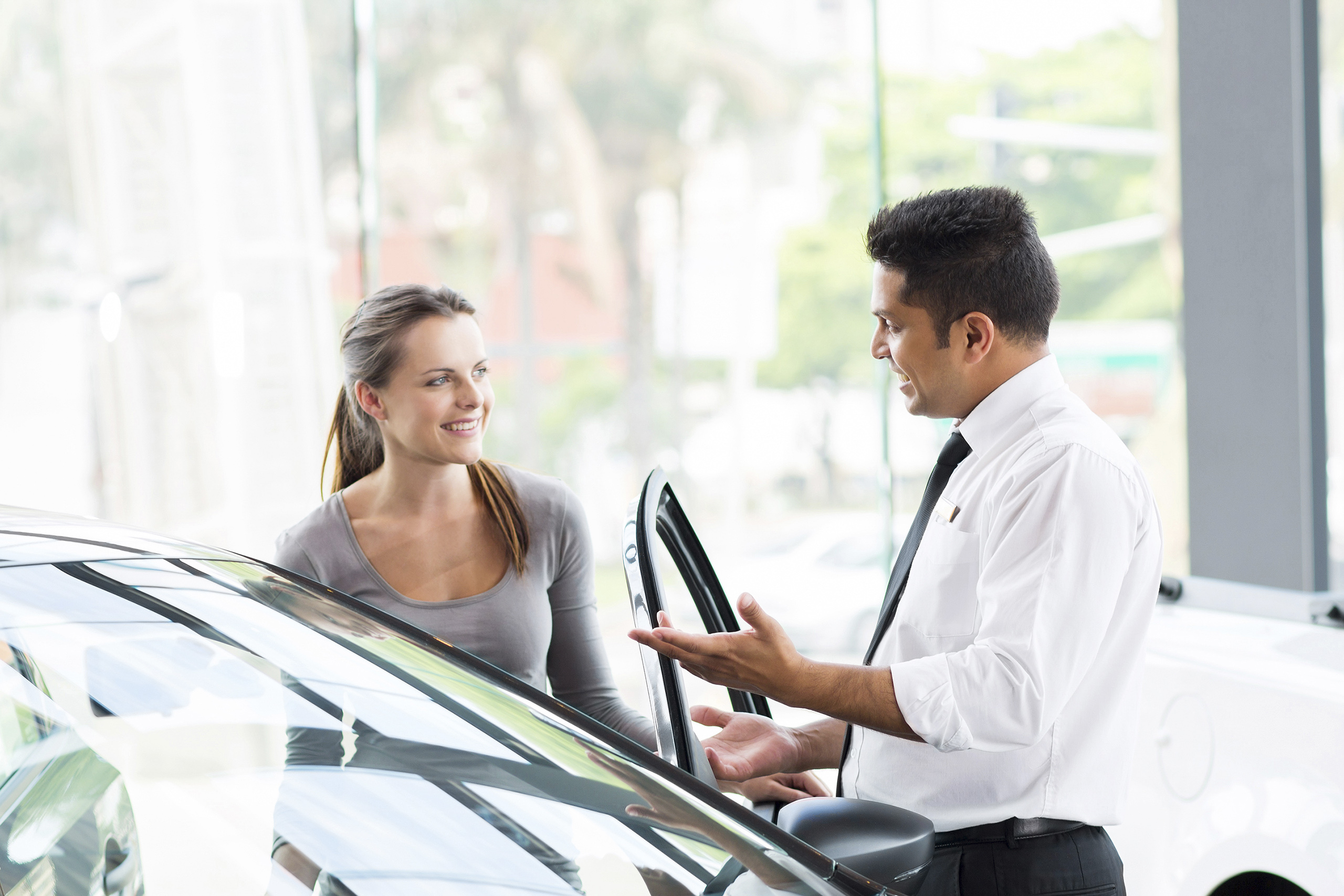 vehicle dealer showing young woman new car